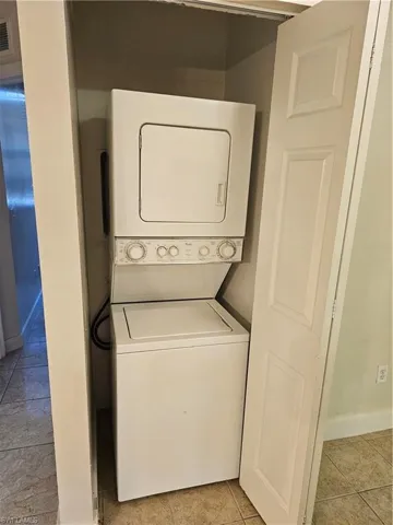 Laundry room with light tile patterned floors and stacked washer / drying machine