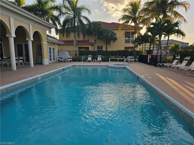 Pool at dusk with a patio, a community pool, and french doors