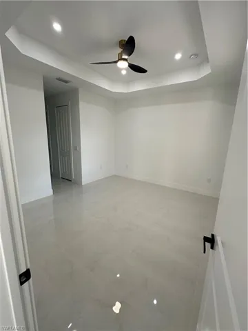 Spare room with ceiling fan and a tray ceiling