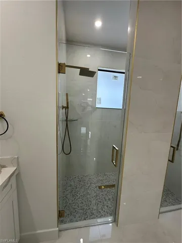 Bathroom featuring tile patterned floors, vanity, and an enclosed shower
