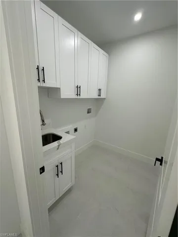 Clothes washing area with cabinets, hookup for a washing machine, hookup for an electric dryer, and sink