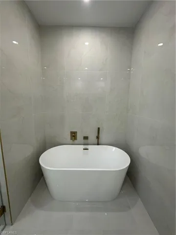 Bathroom featuring a tub and tile walls