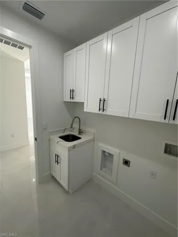 Laundry room featuring electric dryer hookup, hookup for a washing machine, sink, and cabinets