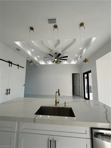 Kitchen with decorative light fixtures, a barn door, a raised ceiling, and sink