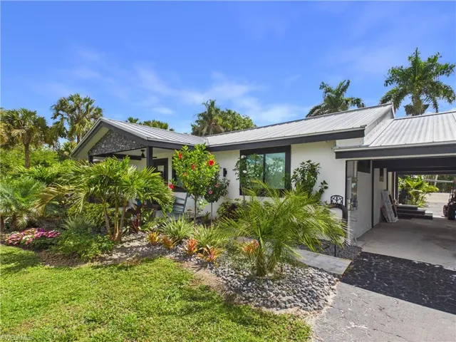Single-story residence featuring a white exterior with dark trim and a metal roof