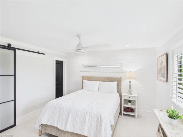 Bedroom featuring a white shiplap accent wall, light wood-finish flooring, and a modern ceiling fan