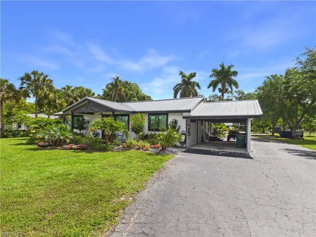 Contemporary exterior with a metal roof, carport, and manicured landscaping