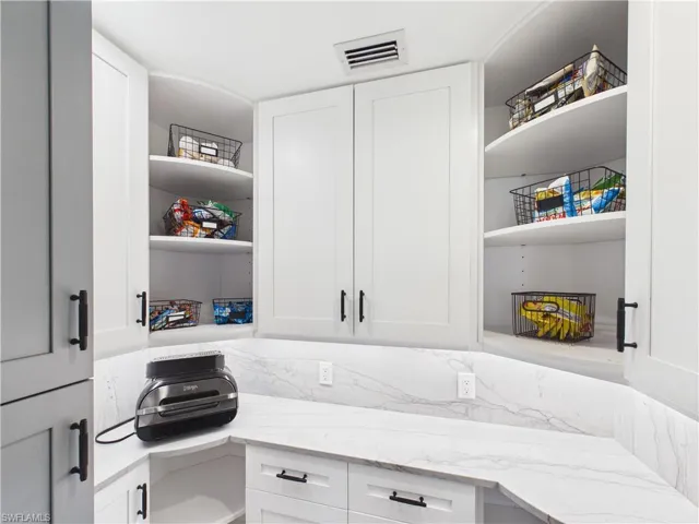 White cabinetry with matte black hardware, under-cabinet lighting, and curved shelving
