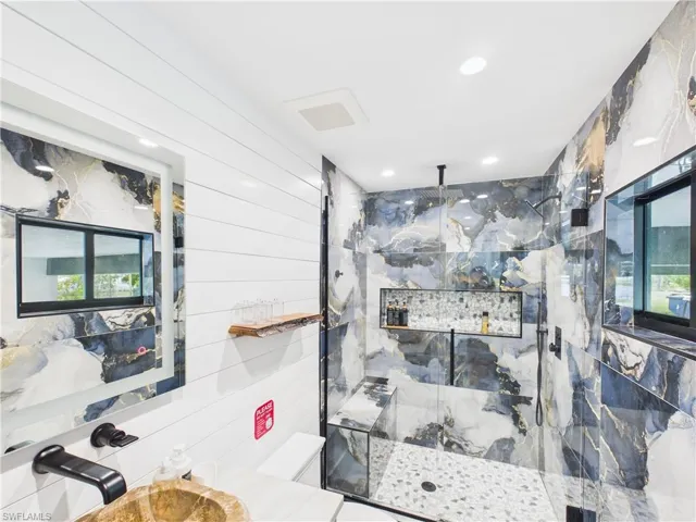 Contemporary bathroom featuring a walk-in shower with patterned wall tile and pebble flooring