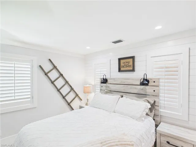 Bedroom featuring white shiplap accent wall, recessed ceiling lighting, and plantation shutters