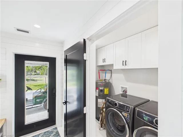 Laundry area featuring white shaker cabinetry, modern dark-finish appliances, and a water heater