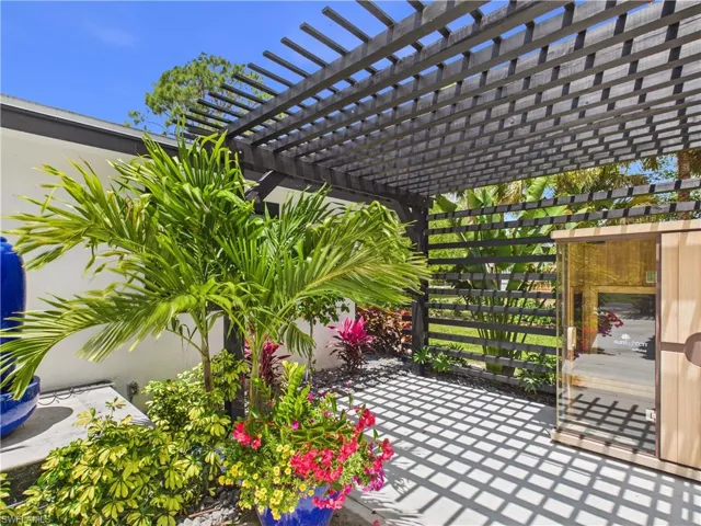 Outdoor living space featuring a dark-stained wood pergola, a privacy screen, and a built-in outdoor sauna with a glass front