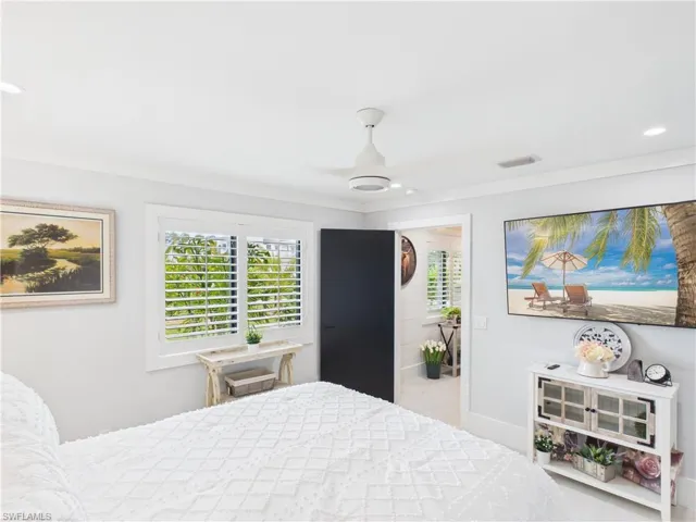 Bright interior space featuring a window with white plantation shutters, a recessed ceiling light, and a white ceiling fan