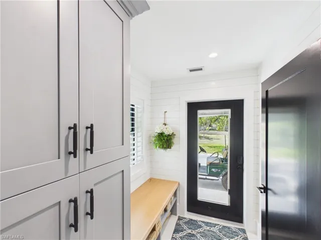Entryway featuring shiplap walls, a built-in wood-finish bench, and gray shaker-style cabinetry with matte black hardware