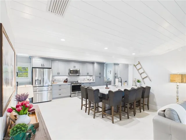 Modern kitchen featuring light gray cabinetry, stainless steel appliances, and a large central island with seating for eight
