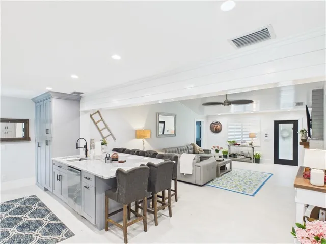 Contemporary kitchen island featuring light grey cabinetry and a light-toned countertop, with an integrated sink and black faucet