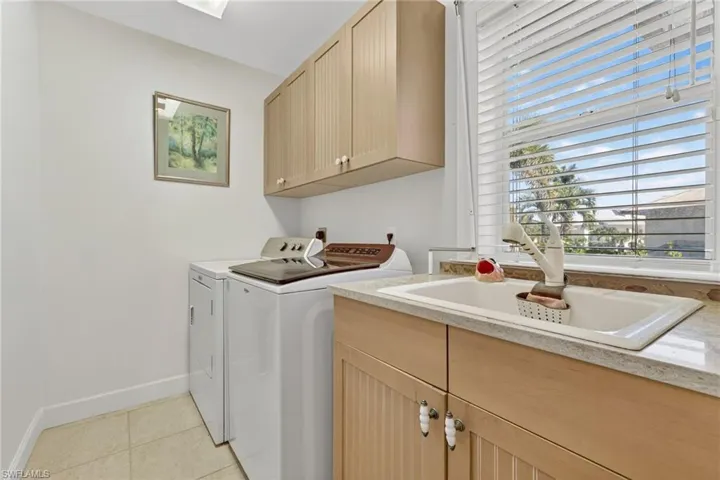 Washroom featuring cabinet space, light tile patterned floors, and washing machine and clothes dryer