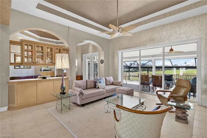 Living area featuring a tray ceiling, light tile patterned flooring, and a sunroom