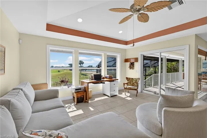 Living room featuring tile patterned flooring, ceiling fan, a tray ceiling, recessed lighting, and an office area