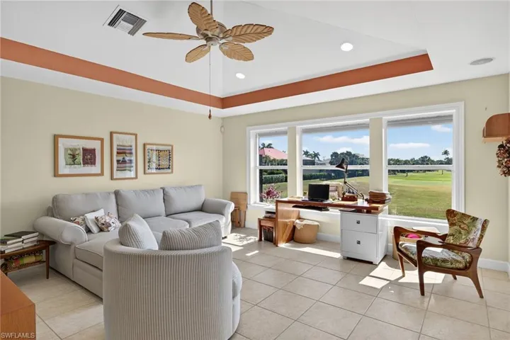 Living area featuring light tile patterned flooring, a raised ceiling, a desk, a ceiling fan, and recessed lighting
