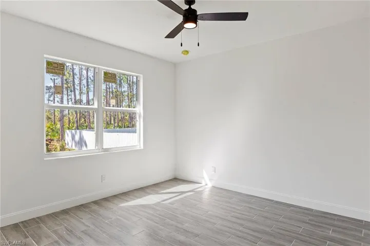 Empty room featuring a healthy amount of sunlight, light hardwood / wood-style floors, and ceiling fan