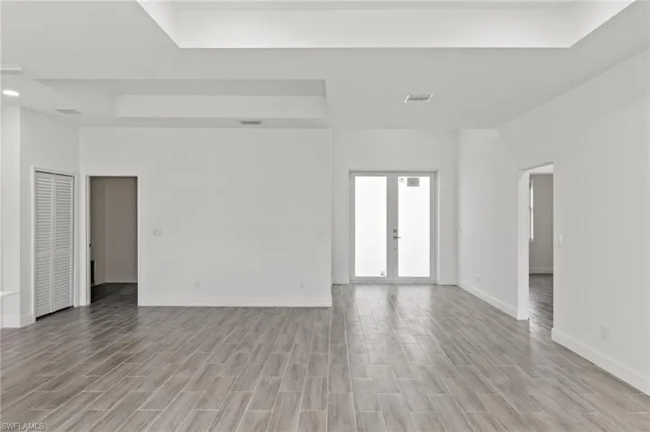 Empty room featuring light hardwood / wood-style floors, french doors, and a raised ceiling