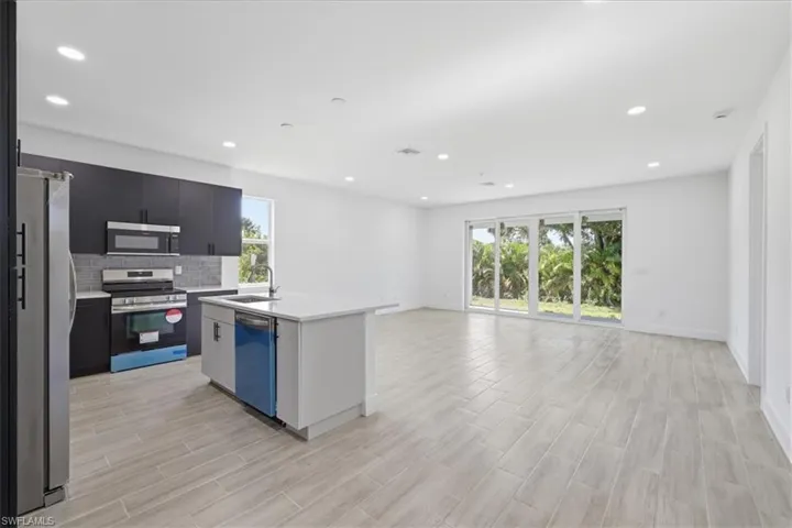 Open-concept kitchen and living area featuring wood-finish tile flooring