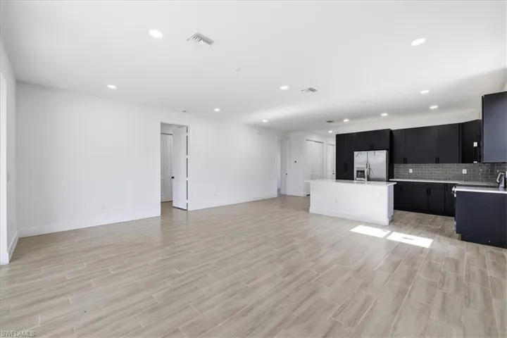 Expansive open-concept living space featuring wood-finish tile flooring, recessed lighting, and a modern kitchen