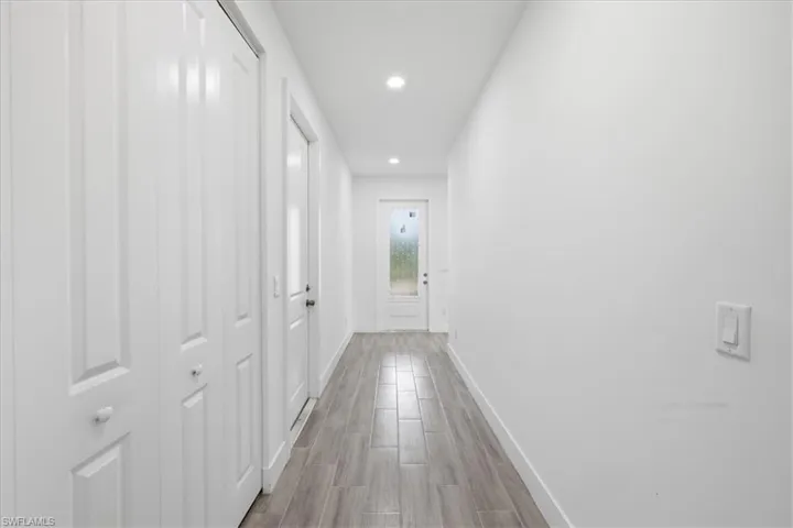 Hallway featuring wood-finish flooring, recessed lighting, white walls, and white panel doors