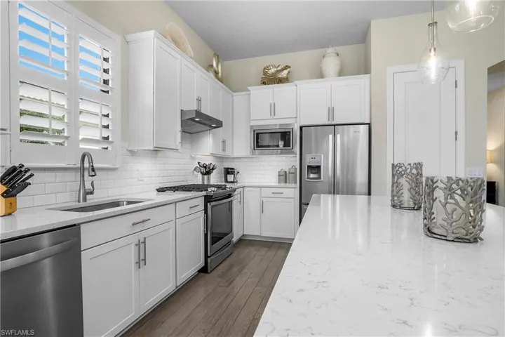 Plantation shutters, designer pendant lighting, and beveled subway tile give this kitchen a classic look.