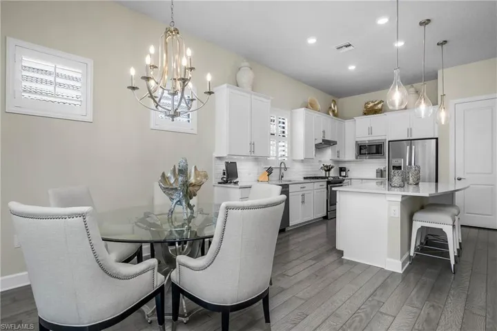Dining room features plantation shutters, designer lighting, and gorgeous engineered hardwood flooring.