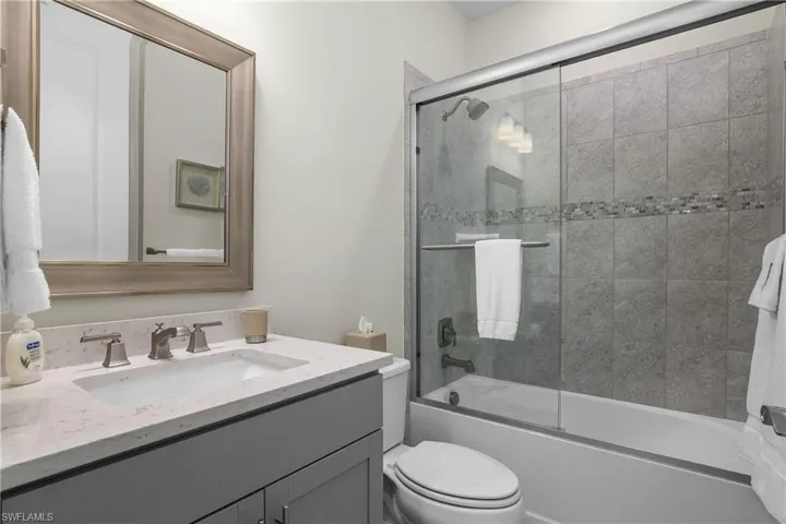 Guest bath with custom mirror, glass shower enclosure, and custom tile work.