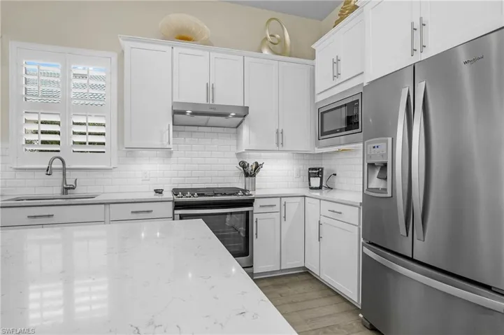 Added kitchen features include white quartz counters, soft close cabinets with pull-out drawers, stainless steel appliances, and natural gas stove/cooktop.