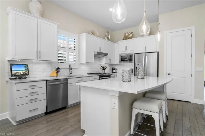 Kitchen is spacious and timeless with white cabinetry, island with plenty of storage, stainless steel whirlpool appliances, and pantry for additional storage.