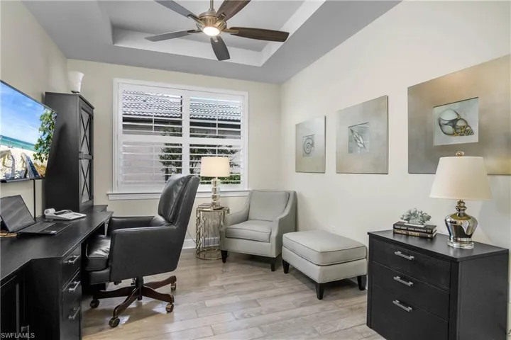 Den features plantation shutters, hardwood flooring and tray ceiling.