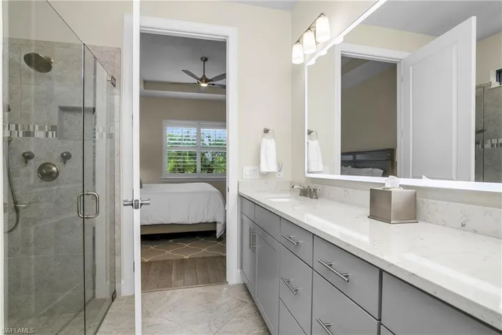 Owner Bath with tile flooring on diagonal, dual sinks quartz counters and custom back-lit mirror.