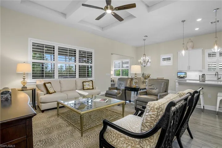 Open family room features plantation shutters, tray ceilings, and lots of natural light.