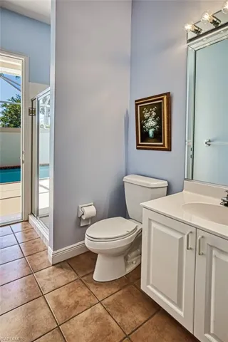 Bathroom featuring a shower with door, vanity, toilet, and tile patterned flooring