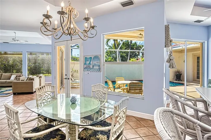 Tiled dining space featuring ceiling fan with notable chandelier