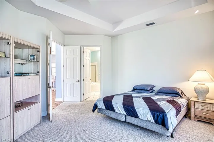 Carpeted bedroom featuring a raised ceiling and ensuite bath