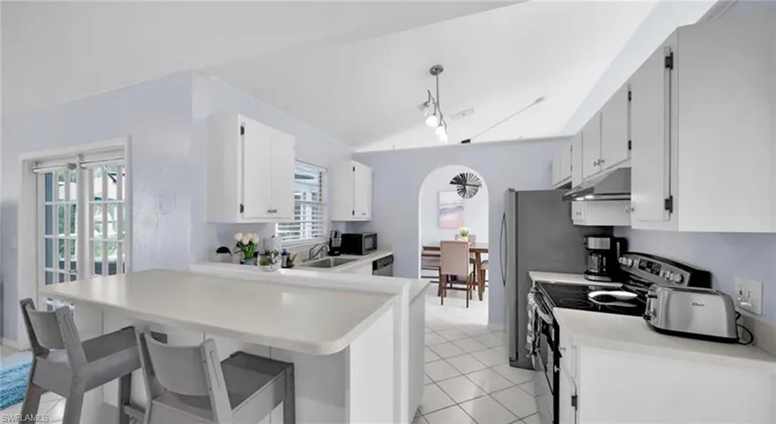 Kitchen with a kitchen bar, stainless steel appliances, a peninsula, and light countertops
