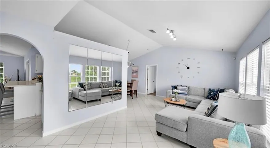 Living room with vaulted ceiling, arched walkways, and light tile patterned floors