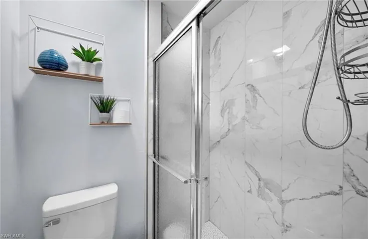 Bathroom featuring a marble finish shower and toilet