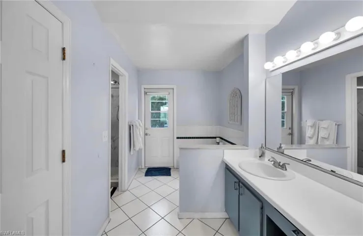Bathroom with light tile patterned floors, vanity, a closet, and a garden tub