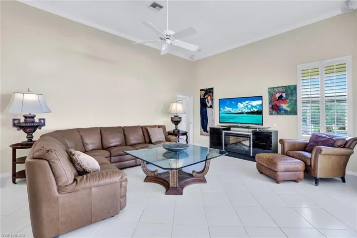Family room featuring light tile floors, high vaulted ceiling, ornamental molding, and disappearing sliders out to the covered lanai and pool area.
