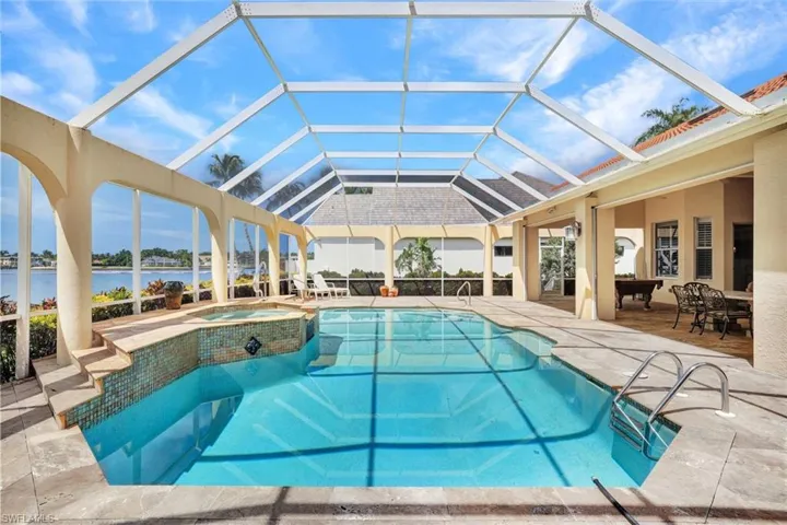 View of the large pool, spill over spa, and stunning views out to Naples Bay.