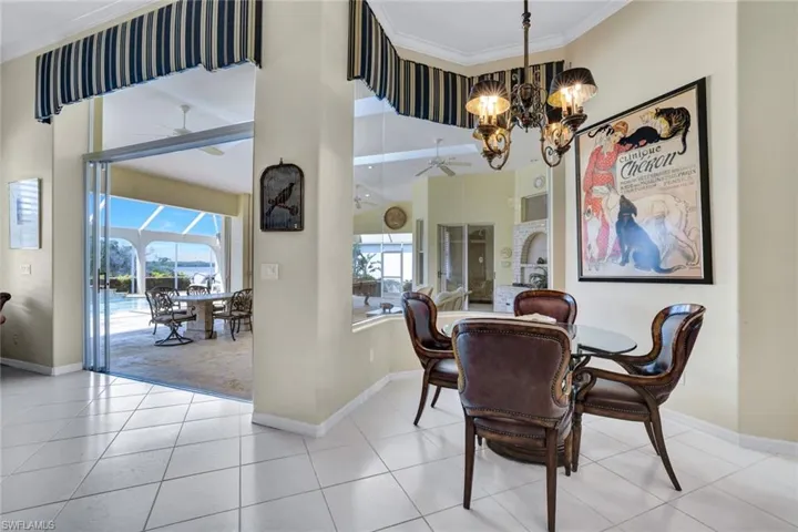 Breakfast nook space with beautiful chandelier, light tile patterned flooring, and plenty of natural light. Views out to Naples Bay!