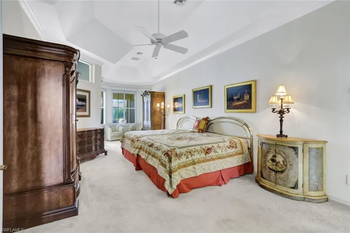 Very large Primary Bedroom featuring vaulted ceiling, light colored carpet, a sitting area, and sliders going out to the covered lanai. This bedroom is on the right wing of the home.