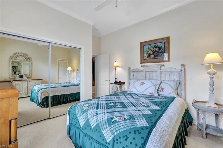 Carpeted 2nd Bedroom with ceiling fan, ornamental molding, and mirrored closet.