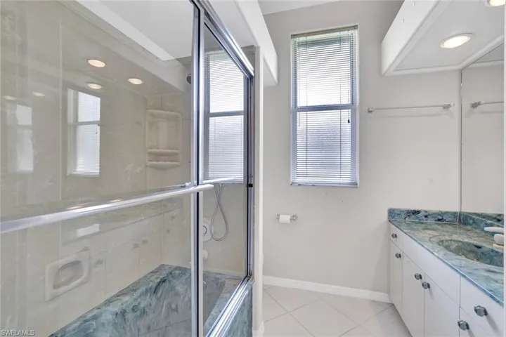 Bathroom featuring a tub and shower with shower door, tile floors, and vanity.  This bathroom sits between bedrooms 3 & 4.